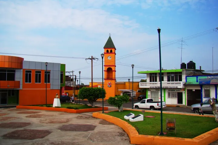 En primer plano, un parque con un reloj de torre en el centro