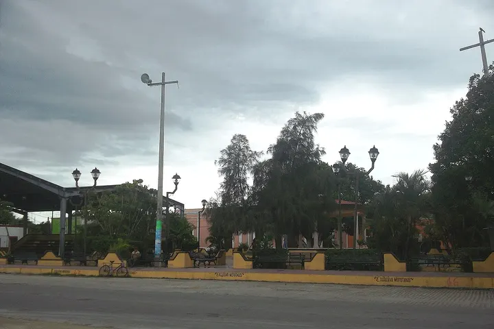 En primer plano, se ve una plaza con una iglesia en el fondo