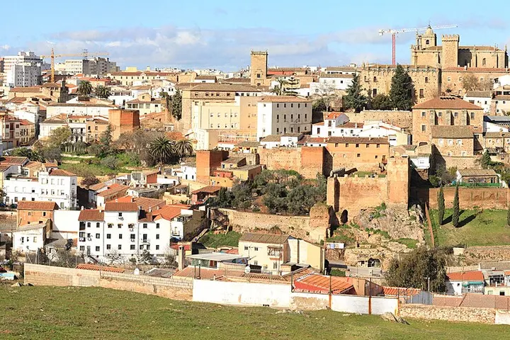En primer plano, un muro de piedra rodea una casa blanca con tejado rojo