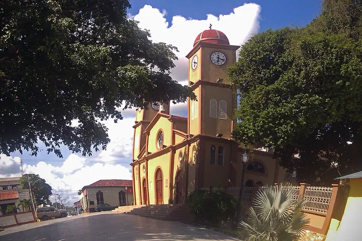 Iglesia colonial beige con torre de reloj y cúpula