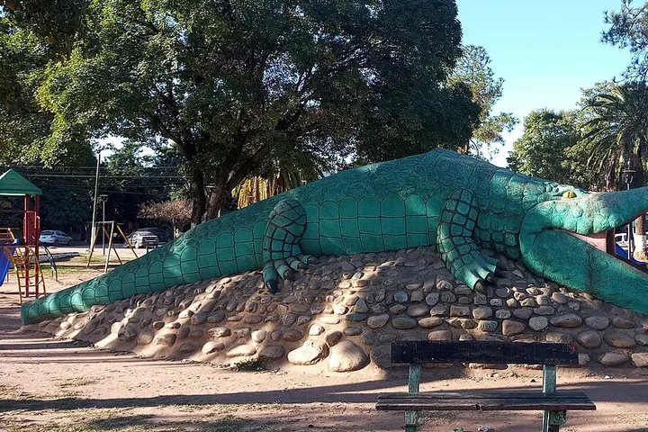 En primer plano, un gran crocodile verde está sobre una montaña de piedras