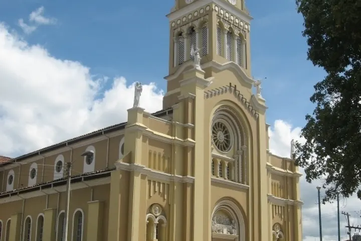 La iglesia de un lugar, con una torre alta y un edificio de color amarillo claro
