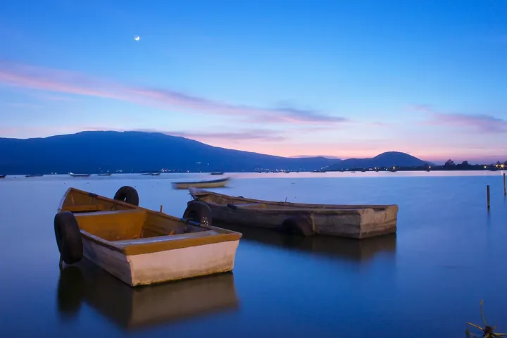 En primer plano, se ve una serie de pequeños botes de madera en el agua