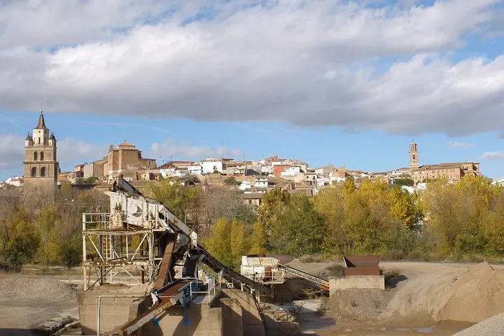 En primer plano, se ve un lugar industrial con una maquinaria en un río, rodeado de árboles
