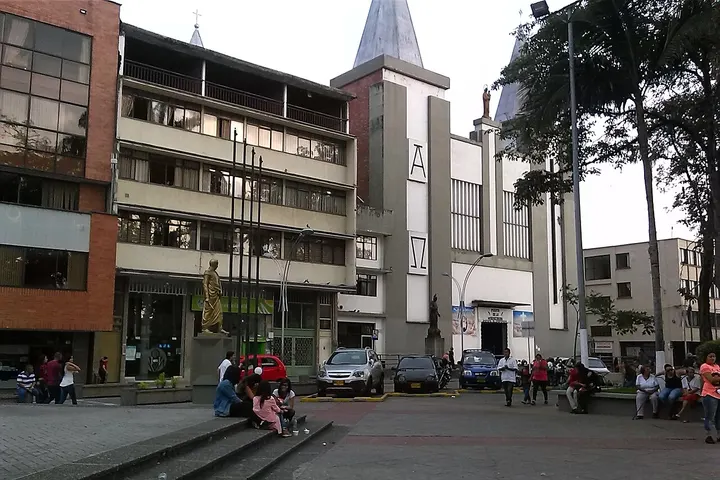 En primer plano, una iglesia con dos torres y una estatua de la Virgen María