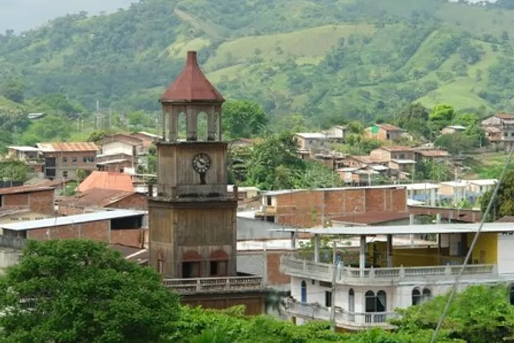 En primer plano, un reloj de torre con un techo rojo sobre una estructura de madera