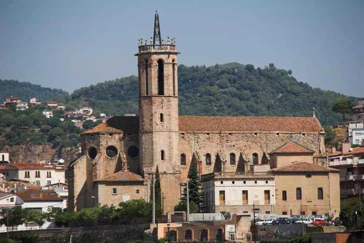 En primer plano, un impresionante edificio de piedra con una torre alta y una fachada con arcos