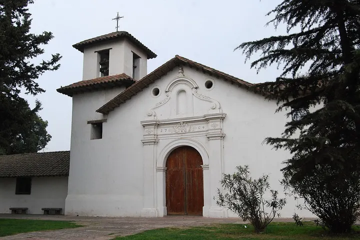 Esta es una iglesia blanca con una puerta de madera y una torre con campanario