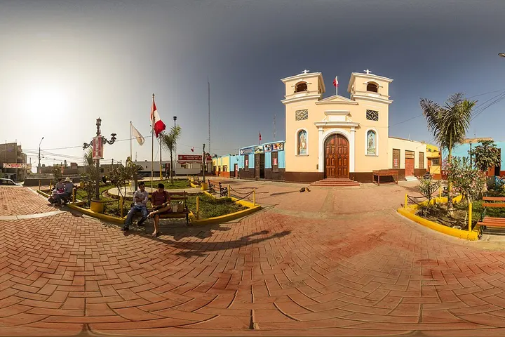 En primer plano, un edificio blanco con un arco y dos torres