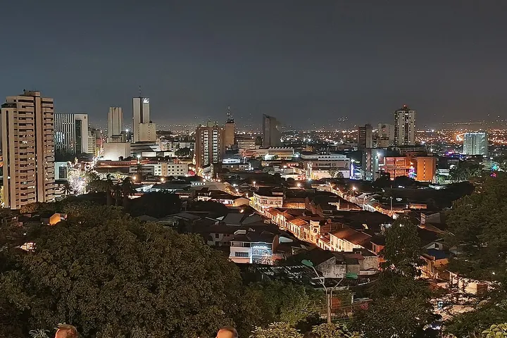 En primer plano, se ven casas con tejados de tejas rojas, rodeadas de árboles