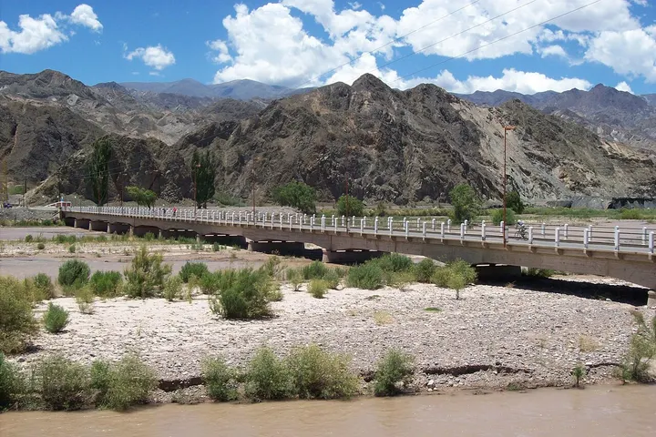 En primer plano, una carretera con un puente sobre un río