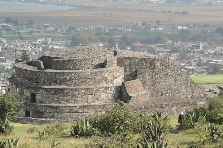 En primer plano, una estructura circular de piedra, con un gran torreón en el centro