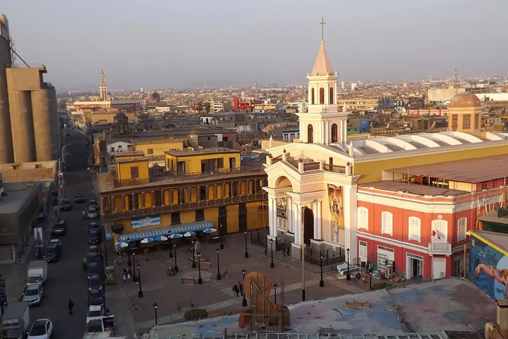 En primer plano, una iglesia con torre y campanario, rodeada de edificios de colores
