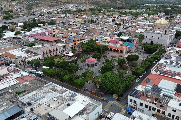 En primer plano, un edificio blanco con una torre de estilo religioso, con una cúpula dorada