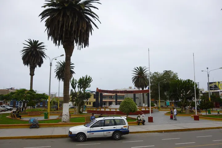Un policía patrulla por una plaza con palmeras y un edificio en el fondo