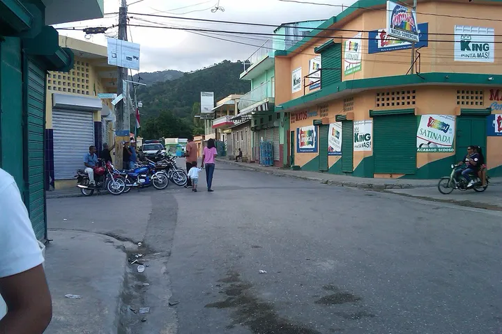 Personas y motocicletas en una calle con edificios de colores