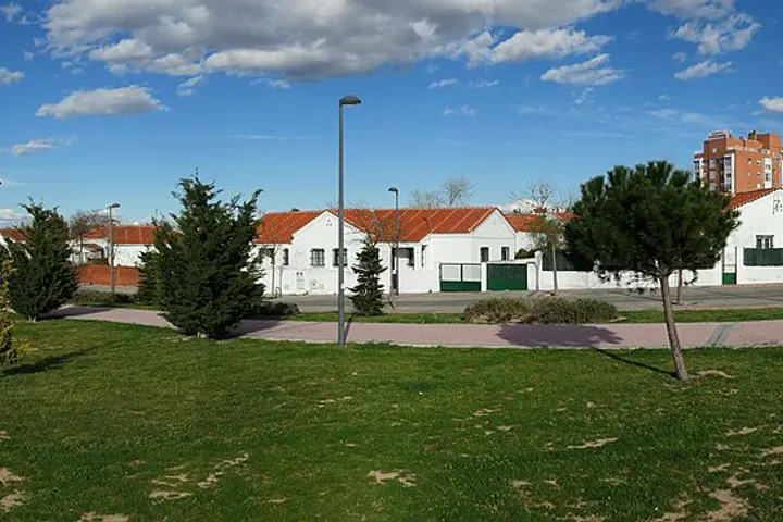En primer plano, se ve un parque con césped y árboles