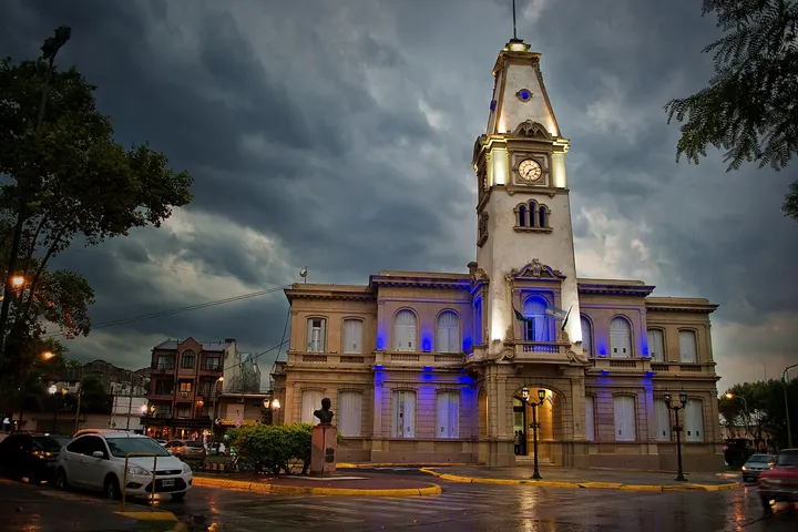 En primer plano, un edificio con un reloj de torre y una entrada iluminada