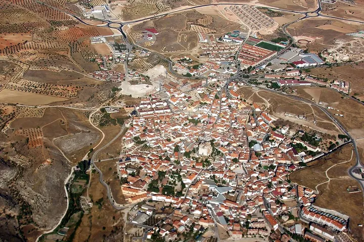 Un pueblo con casas blancas y tejados rojos, rodeado de tierras áridas y sin vegetación