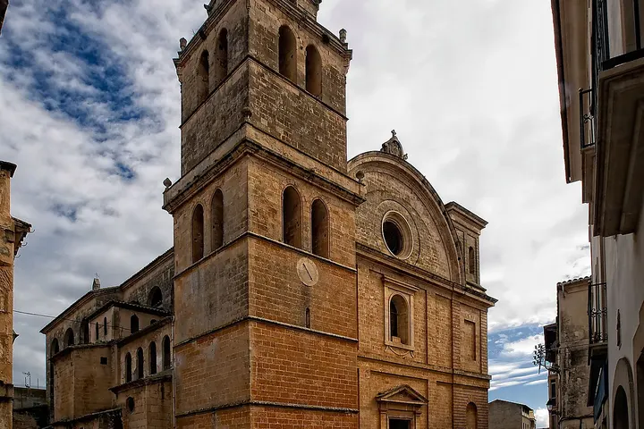 En primer plano, una iglesia de piedra con una torre y una fachada de arcos