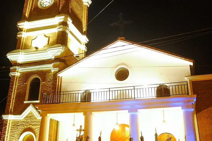 En primer plano, una iglesia con un reloj en su torre