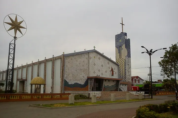En primer plano, una iglesia con un campanario y una estrella dorada