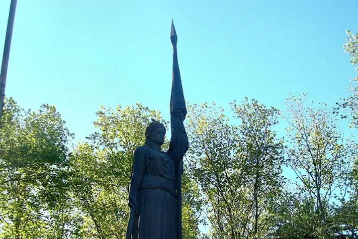 En primer plano, una estatua de una mujer con un lanzador de jabalina