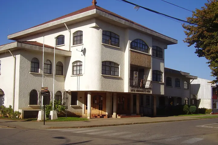 En primer plano, un edificio blanco con una entrada y ventanas