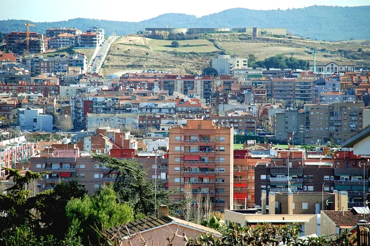 En primer plano, se aprecia una casa con tejado rojo y árboles verdes