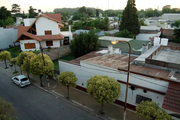 En primer plano, un edificio blanco con un techo rojo y una calle con un coche blanco