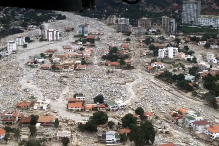 Una ciudad devastada por un desastre natural, con una gran cantidad de escombros y destrucción en primer plano