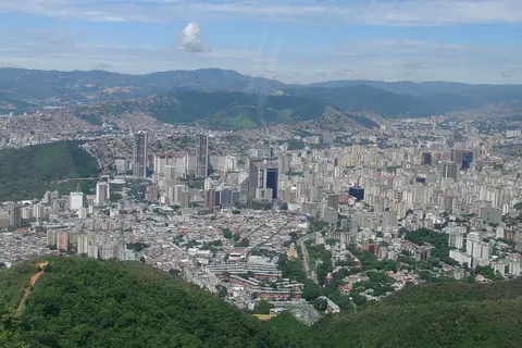 En primer plano, una gran ciudad con muchos edificios y montañas en el fondo