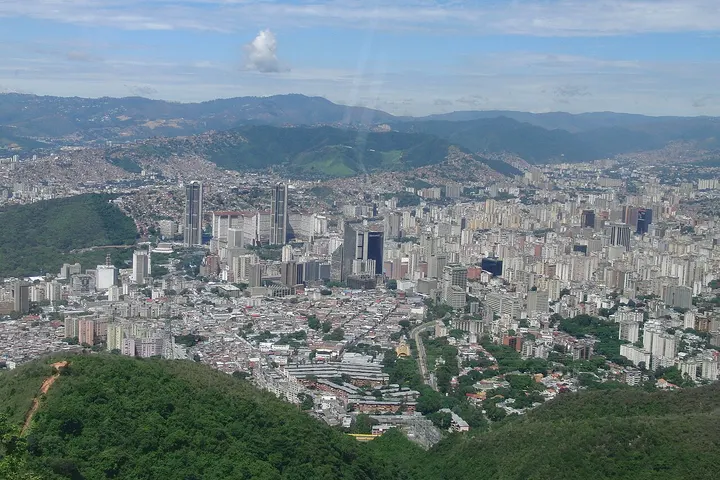 En primer plano, una gran ciudad con muchos edificios y montañas en el fondo