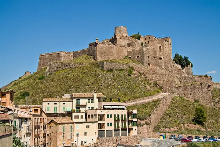 En primer plano, una torre de un castillo de piedra se alza sobre un pueblo de casas de piedra