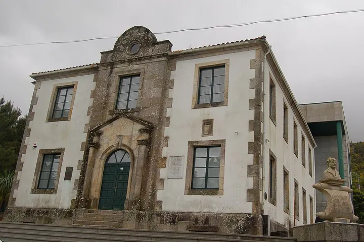 Un edificio blanco con un arco en la entrada y una estatua en la esquina