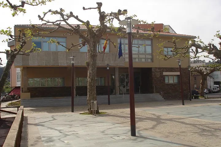 En primer plano, un edificio con una entrada principal y una bandera colgando de un poste