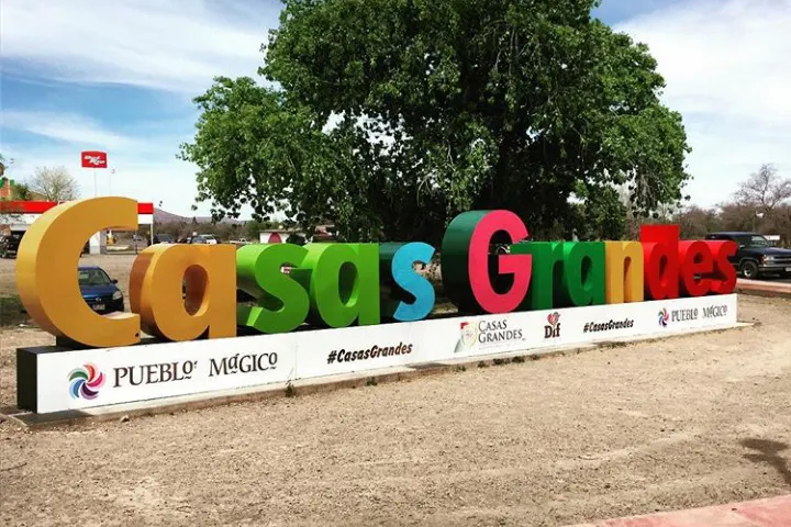 Un gran cartel de letras de colores en la tierra, con un árbol detrás