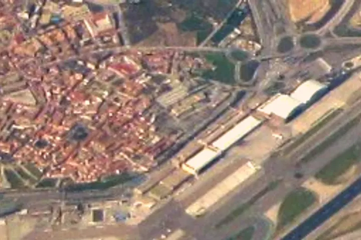 En primer plano, un aeropuerto con una terminal de pasajeros y una pista de aterrizaje