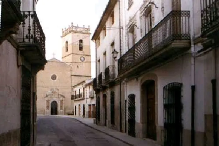 En primer plano, una calle con edificios de piedra blanca y balcones de hierro forjado