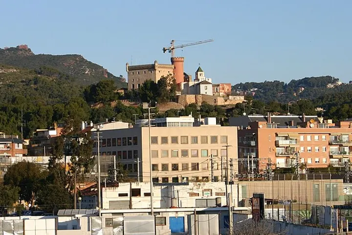 En primer plano, un edificio de oficinas de color blanco con una fachada de ventanas rectangulares