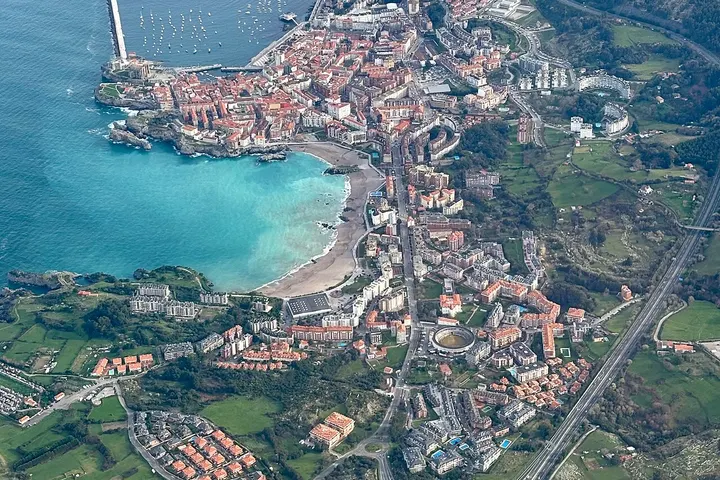 En primer plano, un lago azul rodeado de casas y edificios