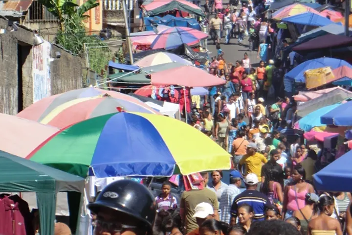 Un mercado al aire libre se ve lleno de gente y sombrillas de colores