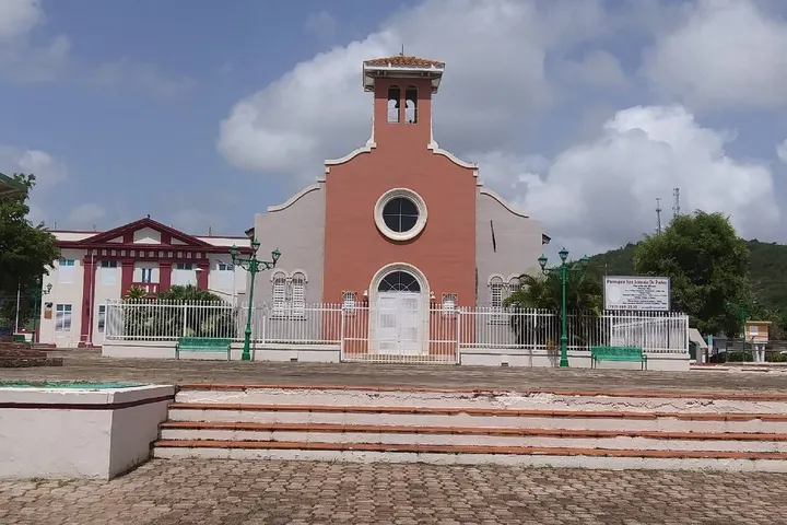 En primer plano, una iglesia con un campanario rojo y una entrada blanca
