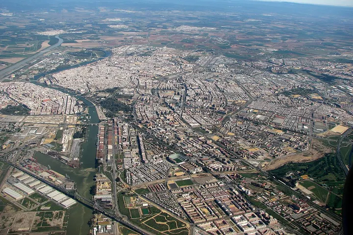 En primer plano, un gran parque con un estadio, rodeado de una gran cantidad de edificios y carreteras