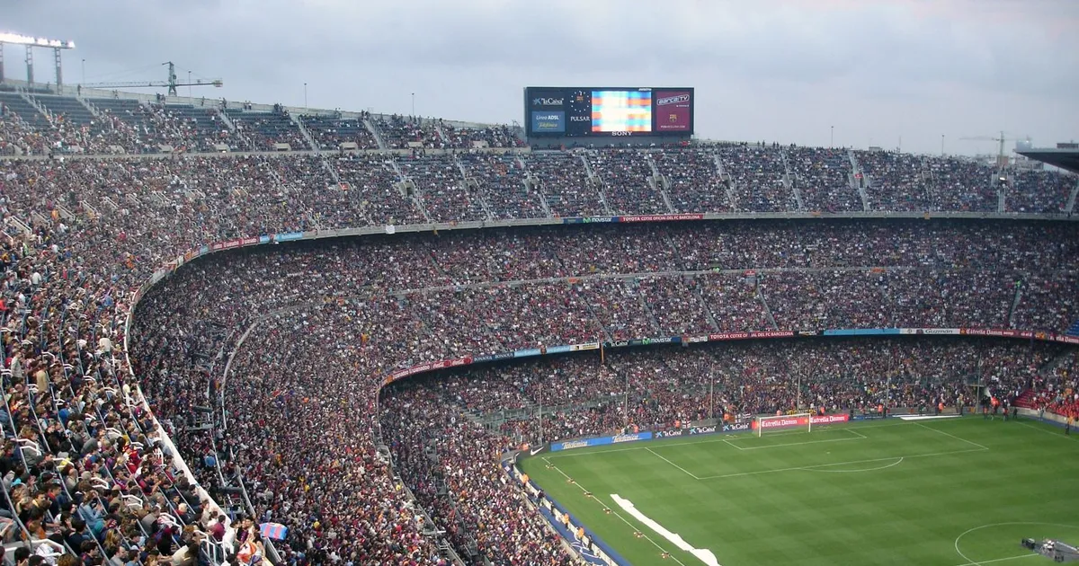 Un estadio lleno de gente, con un campo de fútbol en el centro, en un partido de fútbol