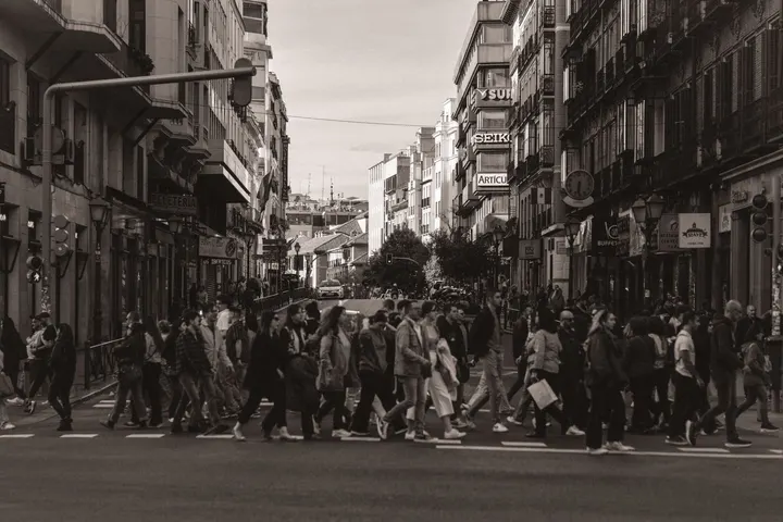 Un grupo de personas camina por una calle de una ciudad, cruzando una calle