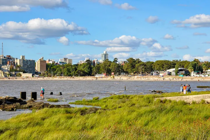 Tres personas caminando en la playa de Punta Carretas, Montevideo