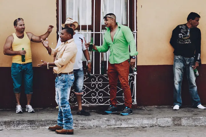 Un grupo de hombres afrodescendientes, en un lugar público, están bebiendo cerveza