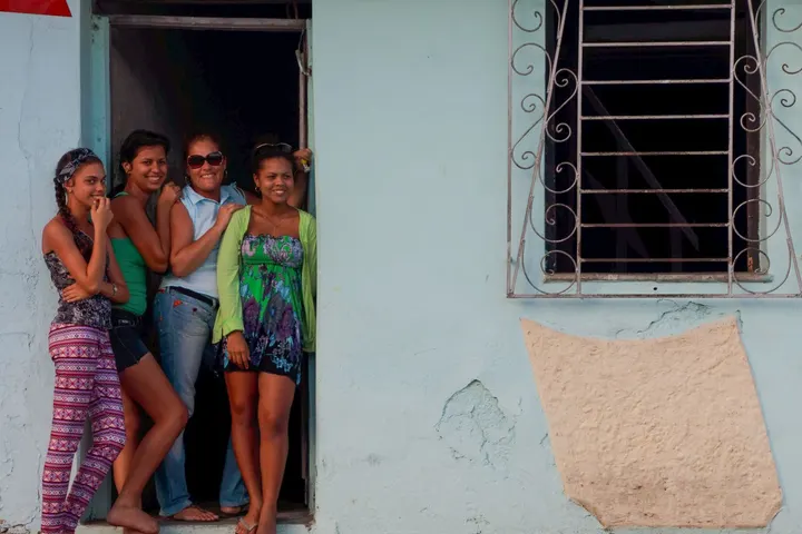 Cuatro mujeres y un hombre están en la entrada de una casa, posando para una fotografía