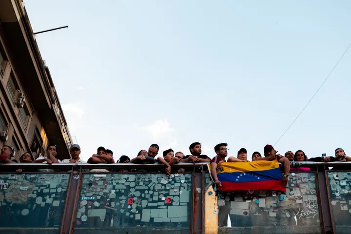 Un grupo de venezolanos en la calle, con la bandera de Venezuela, en un lugar de la ciudad